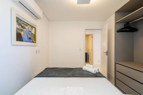 a white bedroom with a bed and a cabinet at Condomínio a beira-mar c/ piscina - SHC in Piçarras