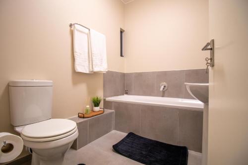 Un baño con inodoro blanco y bañera. en Waterfall Ridge Luxurious Apartment 2 Backup Power, en Midrand