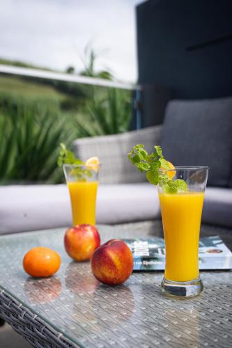 two glasses of orange juice and apples on a table at Terra Vivaz - Porto Bay Villa in Porto Formoso