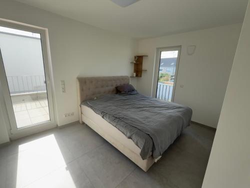 un letto in una camera bianca con due finestre di Villa am Rhein in Monheim a Monheim