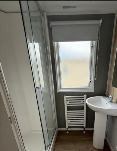 a bathroom with a shower and a sink and a window at zucolli's Caravan at Trecco Bay Holiday Park in Porthcawl