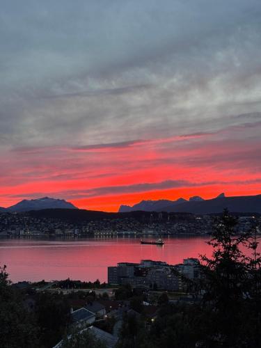 a sunset over a large body of water at Alkove Apartment in Tromsø