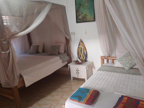 a bedroom with two beds with curtains and a table at fulles guest house in Gili Trawangan