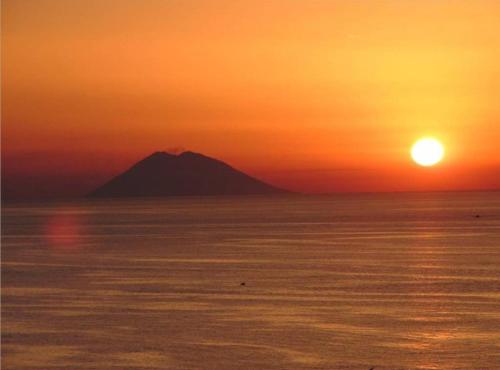 a mountain in the middle of the ocean at sunset at Terrazza Dei Tramonti in Falerna Marina