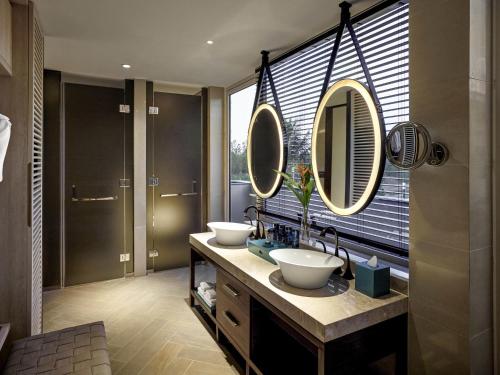 a bathroom with two sinks and two mirrors at Pullman Phu Quoc Beach Resort in Phu Quoc