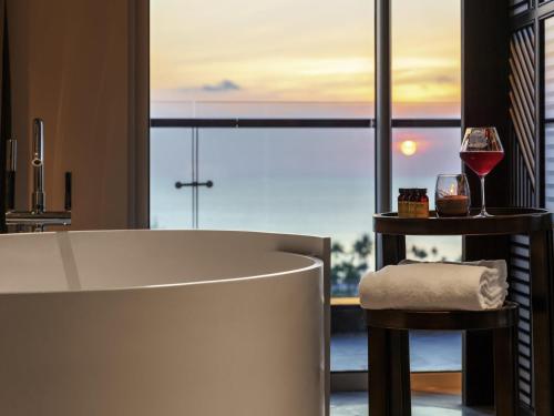 a bathroom with a tub and a glass of wine at Pullman Phu Quoc Beach Resort in Phu Quoc