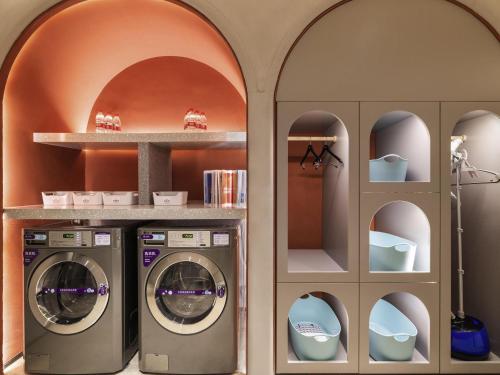 a laundry room with two washing machines and shelves at Mercure Beijing Zhongguancun in Beijing