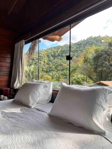 a bed with white pillows in front of a window at Azzuro Hotel in Guaramiranga