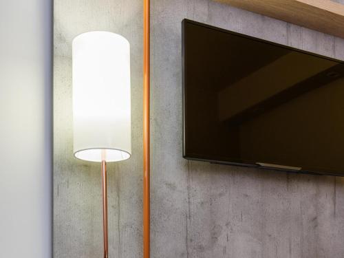 a flat screen tv and a lamp next to a wall at Ibis Budget Perigueux Boulazac in Boulazac