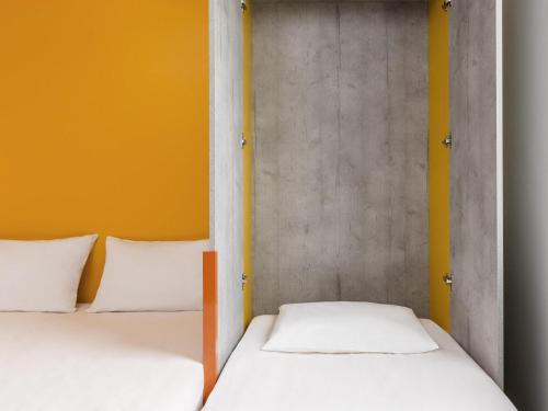 two beds in a small room with yellow walls at Ibis Budget Perigueux Boulazac in Boulazac