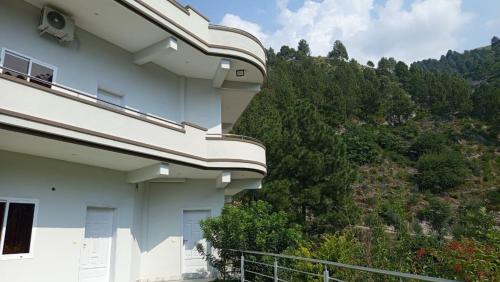 a white building with a hill in the background at At Home in Swat