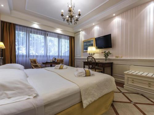 a bedroom with a large white bed and a desk at Mercure Petriolo Siena Terme Spa Hotel in Bagni di Petriolo