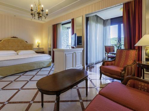 a hotel room with a bed and a living room at Mercure Petriolo Siena Terme Spa Hotel in Bagni di Petriolo
