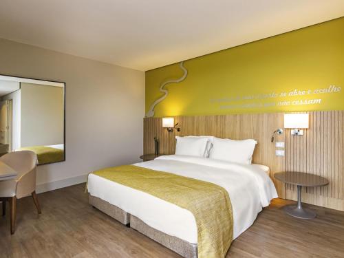 a hotel room with a large bed and a table at Mercure Itajai Navegantes in Itajaí