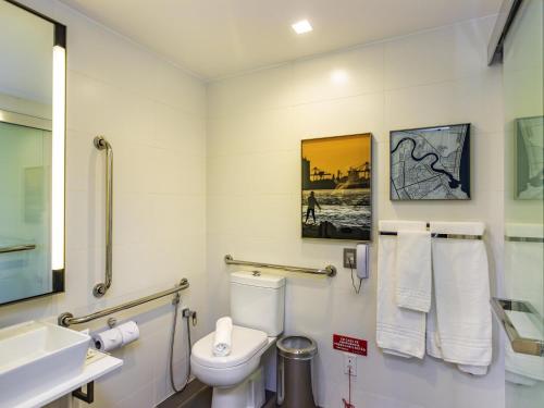 a bathroom with a toilet and a sink at Mercure Itajai Navegantes in Itajaí