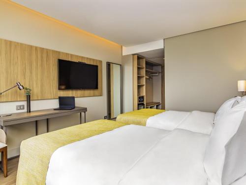 a hotel room with two beds and a television at Mercure Itajai Navegantes in Itajaí