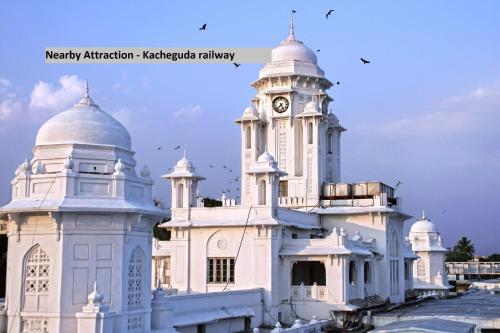 a white building with a clock tower on it at Capital O Wild Wings Hotel Near Omni Hospital Lane Nagole main road in Hyderabad