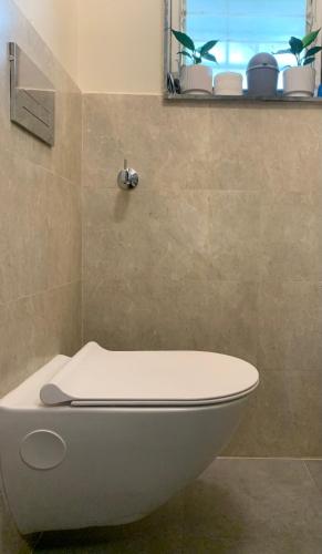 a white toilet in a bathroom with a window at Home Away From Home in Kolhapur
