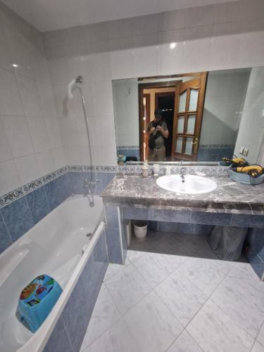 a man taking a picture of a bathroom with a tub and sink at Ilar Appartement in Oulad Akkou