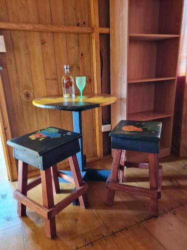 a table and two stools in a room with a table and chairs at Cabañas Bonnysu in Buenos Aires