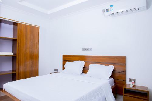 a bedroom with a white bed and a wooden headboard at Kigali Bliss Apartment in Kigali
