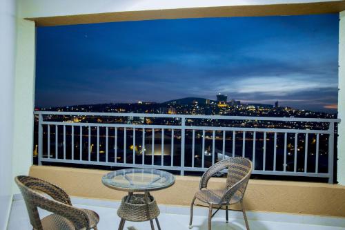 a balcony with chairs and a glass table and a view at Kigali Bliss Apartment in Kigali