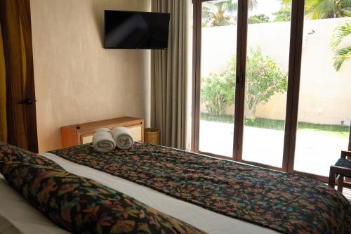a hotel room with a bed with towels and a television at Villa Noyollo - Alberca Privada - Punta Pérula in Pérula