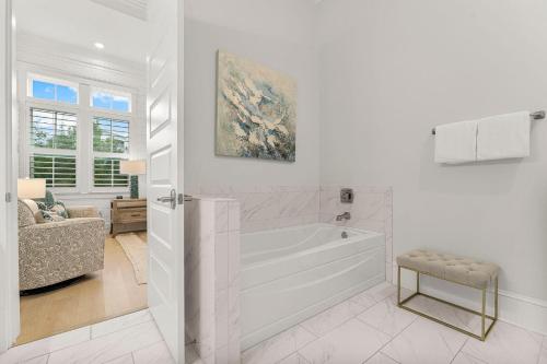 a white bathroom with a tub and a chair at Cottage by the Sea in Watersound Beach