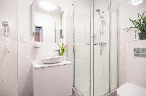 a white bathroom with a shower and a sink at ApartHOTEL Gostyń in Gostyń