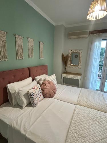 a bedroom with a large white bed with pillows at Daisy Maisonette in Póros Kefalonias