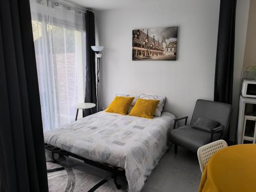 a bedroom with a bed with yellow pillows and a chair at Une pause à Magny appartement de 51 m2 proche Beaune et Dijon NETFLIX gratuit in Magny-lès-Villers