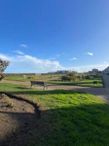 a park bench sitting in the grass near a road at Lowestoft Seaside Escape by Eason Stays, Free Parking next to Sea Front in Oulton
