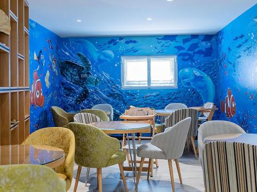 a restaurant with a blue wall with tables and chairs at ibis Styles Chaves in Chaves