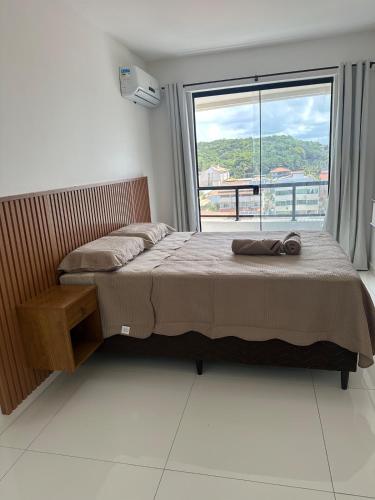 una cama en una habitación con una ventana grande en Lindo apartamento na zona sul de Ilhéus, en Ilhéus
