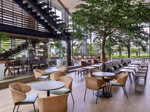 a restaurant with tables and chairs and a tree at Mercure Tangerang BSD City in Tangerang