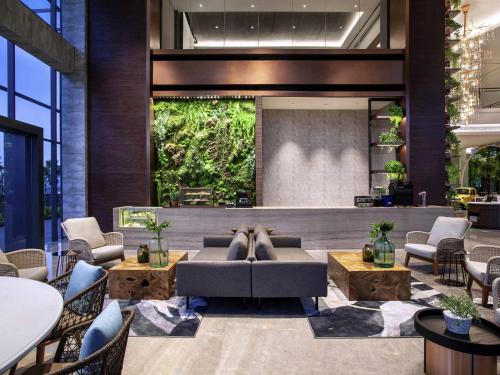 a lobby with a couch and chairs and a large wall at Mercure Tangerang BSD City in Tangerang