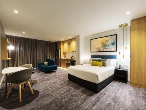 a hotel room with a bed and a desk at Mercure Canberra Belconnen in Canberra
