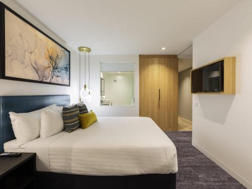 a hotel room with a bed and a tv at Mercure Canberra Belconnen in Canberra