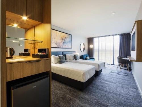 a hotel room with two beds and a kitchen at Mercure Canberra Belconnen in Canberra