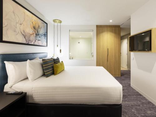 a bedroom with a large white bed and a television at Mercure Canberra Belconnen in Canberra
