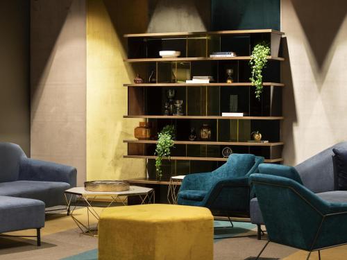 a room with blue chairs and a shelf with plants at Mercure Canberra Belconnen in Canberra