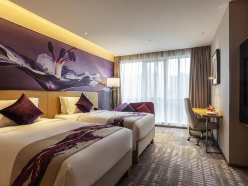 鄭州市にあるNovotel Zhengzhou Airportのベッド2台と机があるホテルの部屋