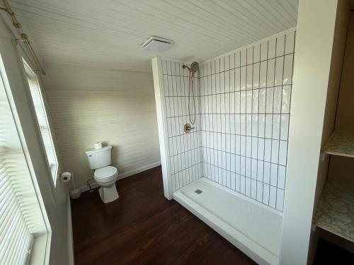 Un baño blanco con inodoro y ducha. en Juanitas Garden Cottage, en Jonesville