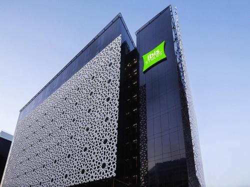 a building with a green sign on the side of it at ibis Styles Dubai Airport Hotel in Dubai