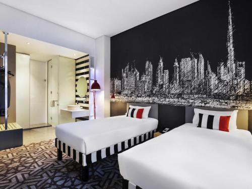 a hotel room with two beds and a black wall at ibis Styles Dubai Airport Hotel in Dubai