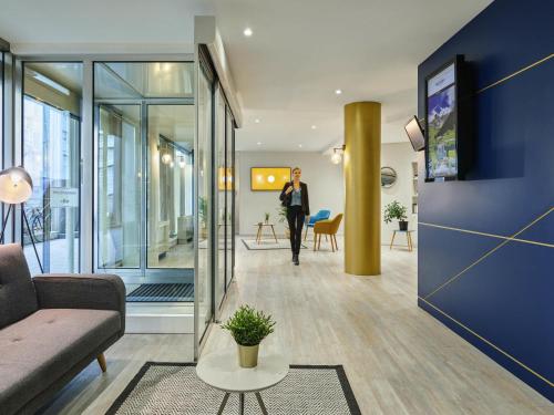a woman walking down a hallway in a building at Residence Mercure Paris La Defense Grande Arche in Nanterre