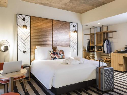 a bedroom with a large white bed and a laptop at Mercure Luxembourg Off Kirchberg in Luxembourg