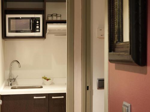 a kitchen with a sink and a microwave at Residence Mercure Paris La Defense Grande Arche in Nanterre