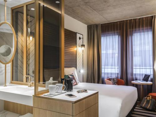 a hotel room with a large bed and a sink at Mercure Luxembourg Off Kirchberg in Luxembourg