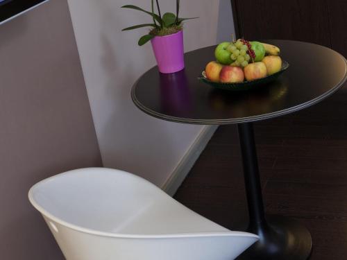 a table with a bowl of fruit on it next to a chair at Residence Mercure Paris La Defense Grande Arche in Nanterre